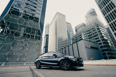 Black porsche 911 parked in tall buildings near the road during the day
